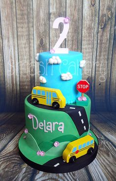 a two tiered birthday cake with cars and buses on the side, along with a stop sign