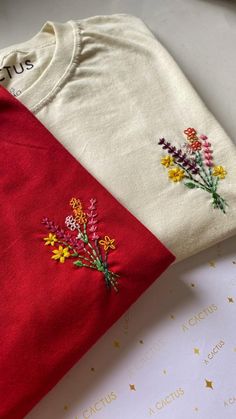 two t - shirts with embroidered flowers on them, one is red and the other is white