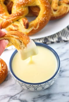 a person dipping cheese on pretzels in a bowl