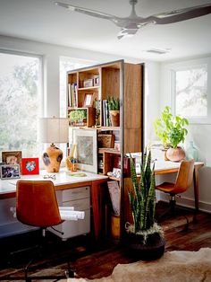 a home office with desk, bookshelf and plants