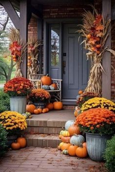 a front porch decorated for fall with pumpkins and corn stalks