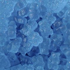 blue gummy bears are piled together in the middle of some water droplets on top of each other