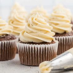 chocolate cupcakes with white frosting on top and a spatula next to them