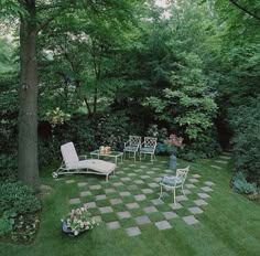 a person standing in the middle of a yard with lawn furniture and flowers on it