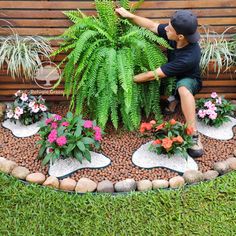 a young boy sitting on a bench next to some plants