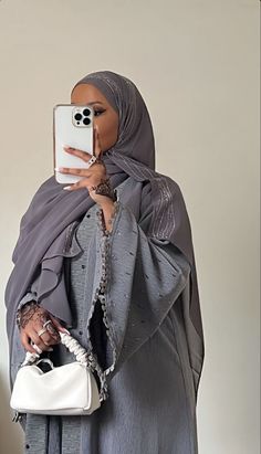 a woman wearing a hijab and holding a cell phone