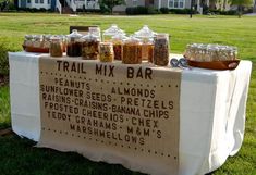 a table topped with jars filled with food on top of a lush green park covered in grass