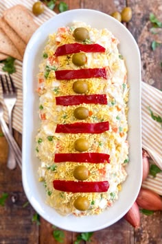 a white plate topped with an appetizer covered in cheese and olives