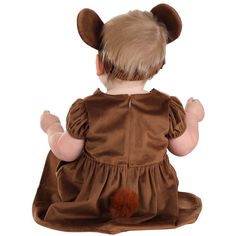 a baby dressed in a brown dress with ears on it's head sitting down