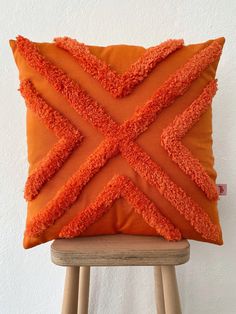 an orange pillow on top of a wooden stool