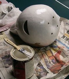 a white helmet sitting on top of a newspaper next to a paint can and brush