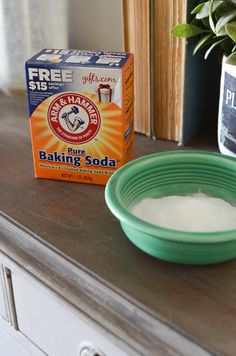 a bowl of baking soda sitting on top of a table next to a box of baking soda