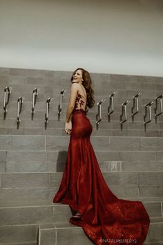 a woman in a red dress standing on some stairs