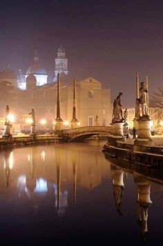 the city is lit up at night and reflecting in the water