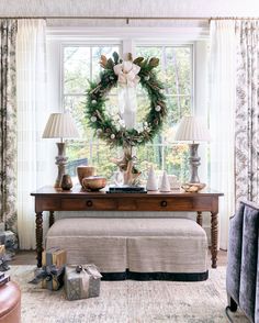 a christmas wreath sitting on top of a table next to two lamps and a bench