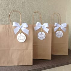 three brown paper bags with white bows and tags on them, sitting on a shelf