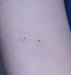 two small white flowers on the side of a woman's thigh