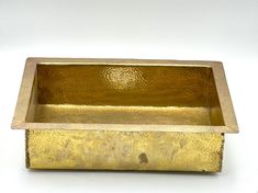 a gold colored metal container on a white surface with no one in it or someone else