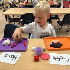 a young boy sitting at a table playing with toys