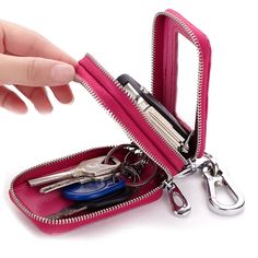 a pink zippered case with keys and scissors in it is being held by a person's hand