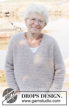 an older woman standing in front of a body of water