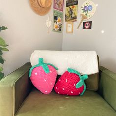 two knitted strawberries sit on the back of a green couch in a living room