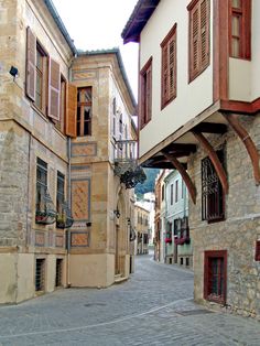 an alleyway between two buildings with wooden shutters on each side and stone floors