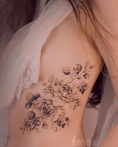 a close up of a woman's back with flowers on her left arm and chest