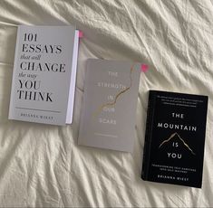 three books laying on top of a bed next to each other in front of a white sheet