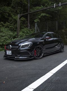 a mercedes cla is parked on the side of the road in front of some trees