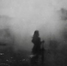 a black and white photo of a person in the fog