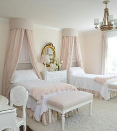 two white beds in a bedroom with pink drapes