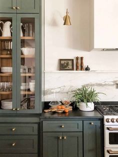 a kitchen with green cabinets and an oven in the center, surrounded by white marble countertops