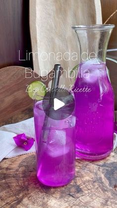 two pitchers filled with purple liquid sitting on top of a wooden table next to each other