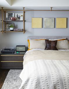 a bed sitting in a bedroom next to a wall mounted book shelf with pictures on it