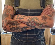 a man with tattoos is holding his arms crossed