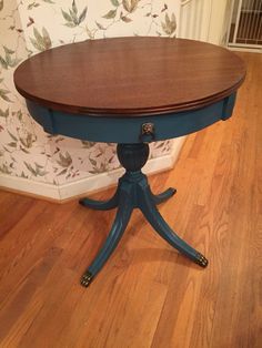 a wooden table sitting on top of a hard wood floor next to a floral wallpaper