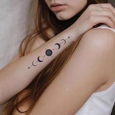 a woman with a tattoo on her arm that has the moon and stars tattooed on it