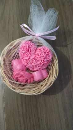 pink soaps in a mesh bag on a wooden table with a bow and ribbon