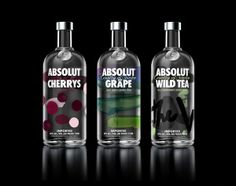 three bottles of absolut and grape vodka on a black background with the words absolut in bold colors