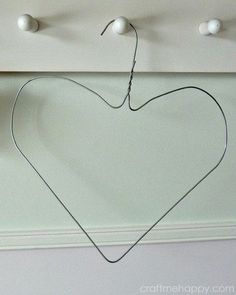 a heart hanging on a wall with three balls attached to the hooks and one string