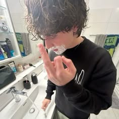 a young man shaving his face in the bathroom