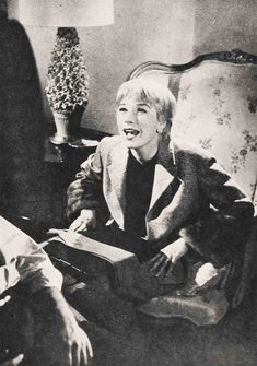 an old black and white photo of a woman sitting in a chair laughing while holding a book