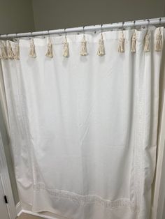 a white shower curtain with tassels hanging from it