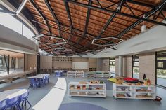 the inside of a school with tables, chairs and bookshelves on each side