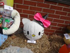 a hello kitty pumpkin with a pink bow on it's head sitting in hay