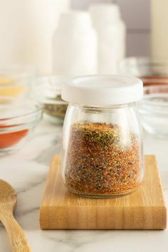 a jar filled with spices sitting on top of a wooden cutting board