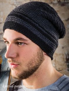 a man with a beard holding a skateboard in front of his face and wearing a knitted hat