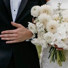 the bride and groom are holding bouquets of white flowers in their hands as they stand close to each other