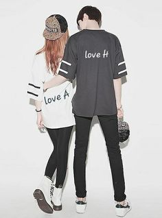 a man and woman standing next to each other in front of a white wall with the words love at written on it